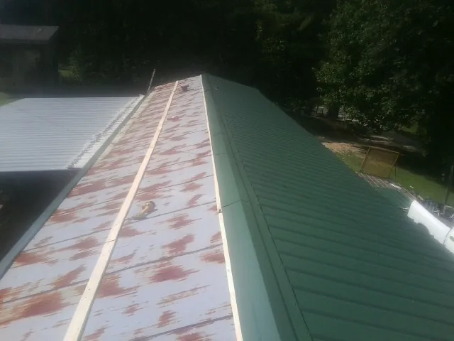 Old rusted panels beside newly installed green metal roofing — Wind Damage Roof Repair by Roofing Brothers in Turtle Creek