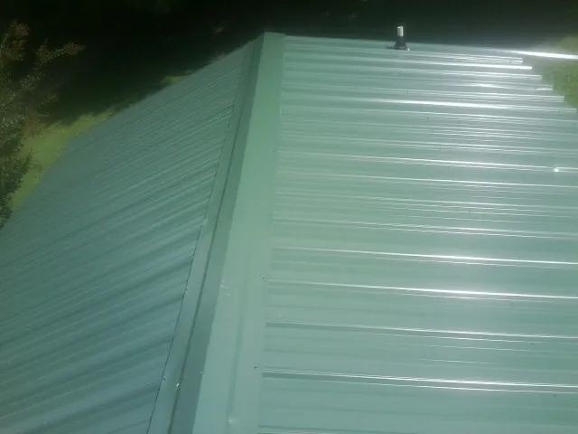 New green metal panels meeting at the ridge of a roof — Flat Roof Repair work by our crew in Turtle Creek
