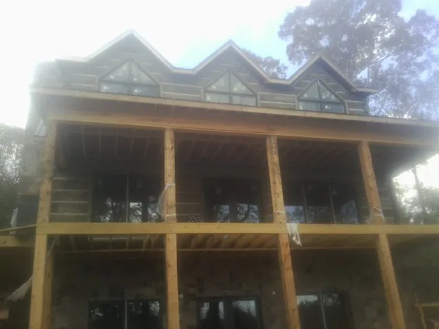 Dormers and porch framing on a large log home under construction — Roof Coating work by our crew in Turtle Creek