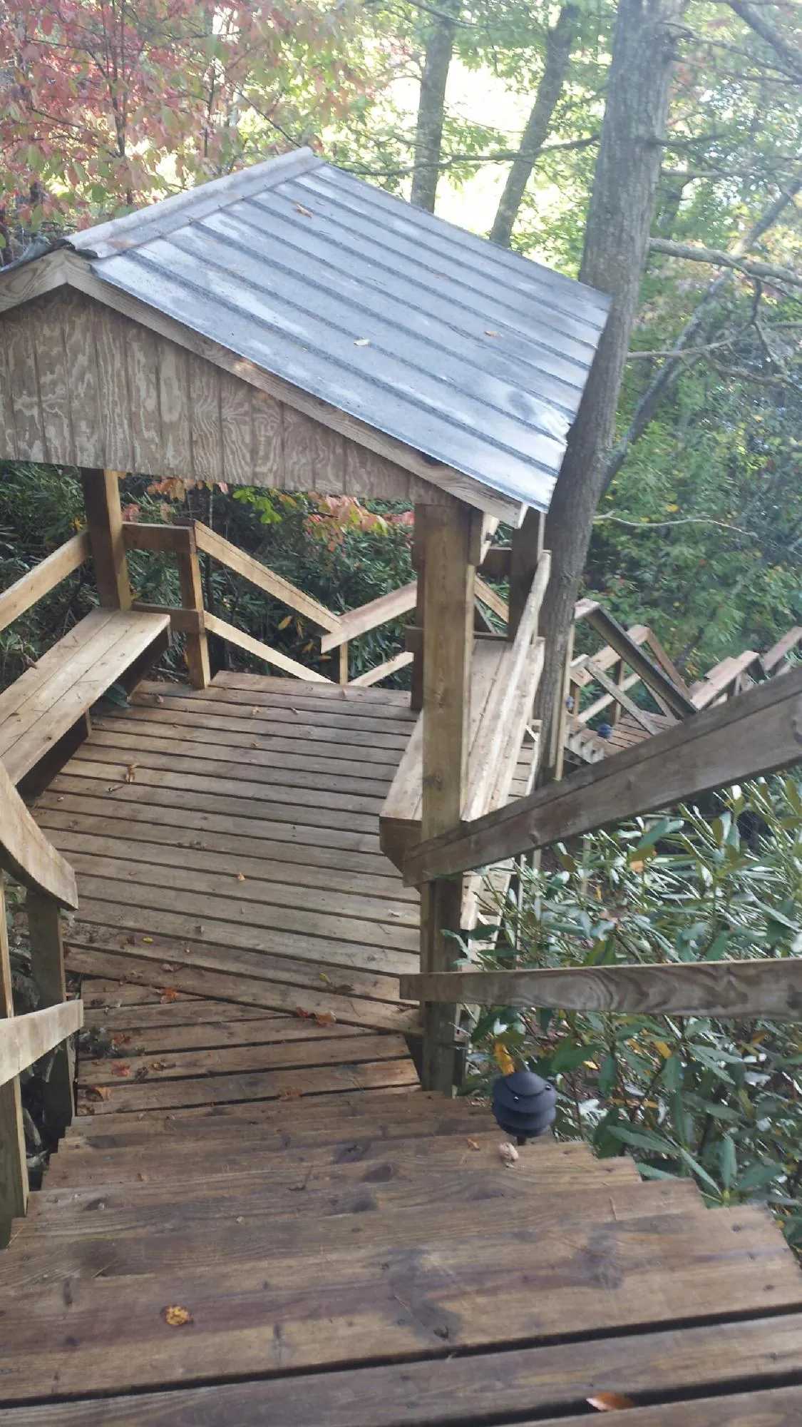 Metal roofed shelter over wooden steps on a wooded walkway — Skylight Repair & Installation work by our crew in Turtle Creek