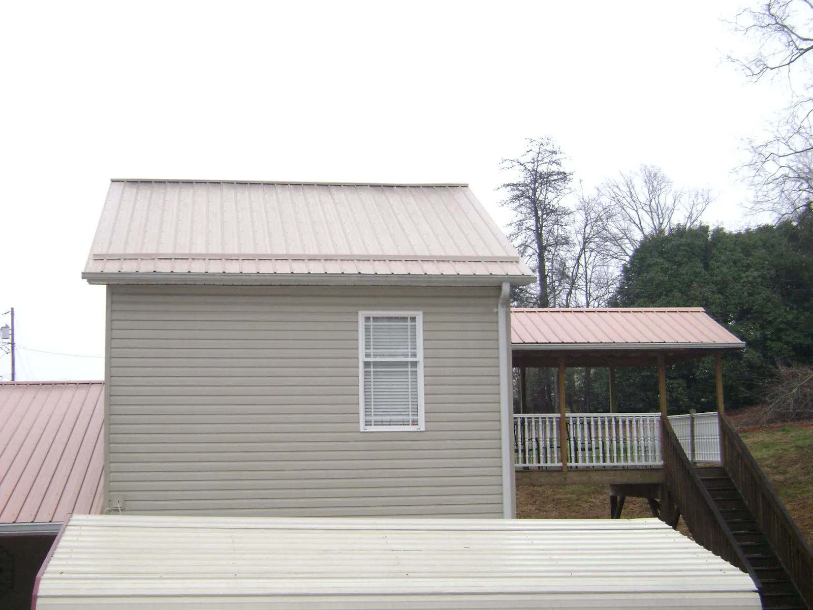 Tan metal roofs on a two story addition and attached porch, from a Roof Replacement job in Turtle Creek